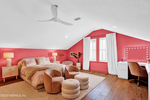 bedroom featuring a textured ceiling, visible vents, a ceiling fan, vaulted ceiling, and wood-type flooring