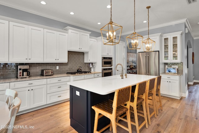 kitchen with crown molding, a sink, light wood finished floors, white cabinets, and an inviting chandelier
