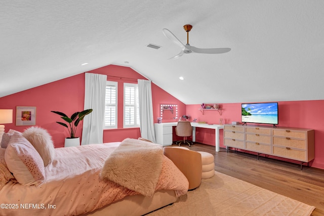 bedroom featuring a ceiling fan, wood finished floors, a textured ceiling, lofted ceiling, and visible vents