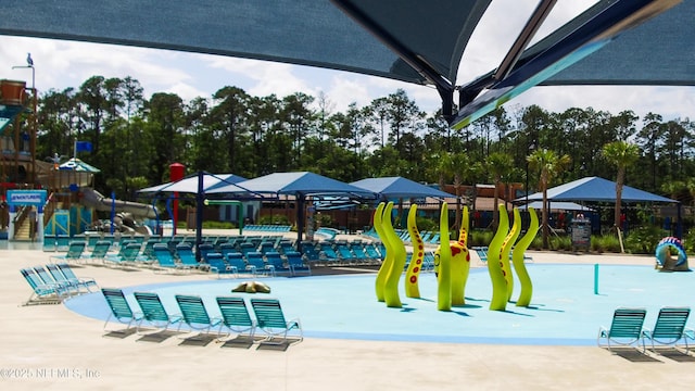 pool with a patio, a water slide, playground community, and a water play area