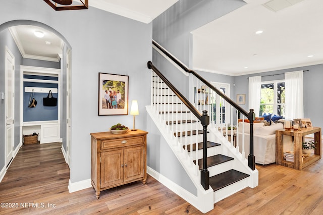 stairs featuring ornamental molding, arched walkways, wood-type flooring, and visible vents