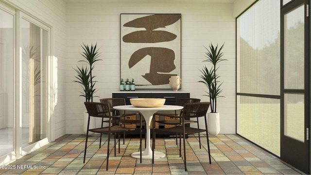 dining area featuring a healthy amount of sunlight and brick floor