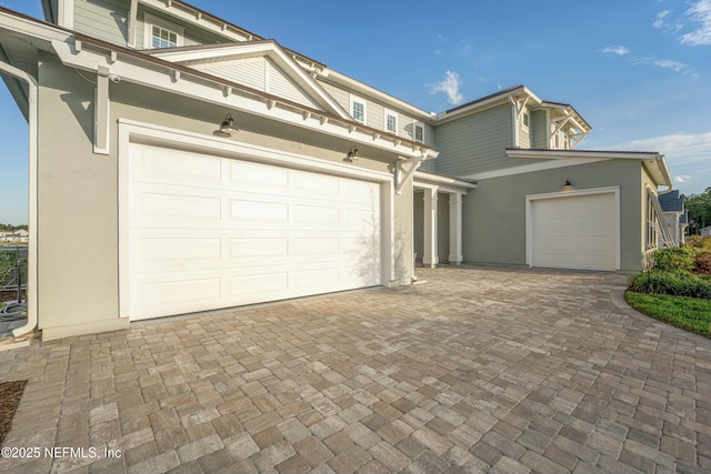 exterior space with stucco siding, an attached garage, and decorative driveway