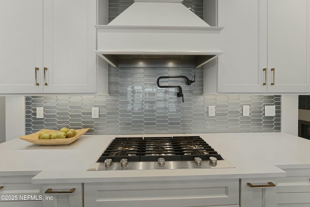 kitchen with custom exhaust hood, decorative backsplash, light countertops, and stainless steel gas stovetop