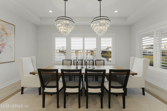 dining space featuring a tray ceiling, recessed lighting, light wood finished floors, and a chandelier