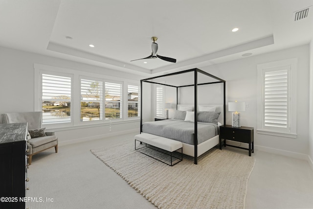 bedroom featuring visible vents, baseboards, a tray ceiling, and carpet floors