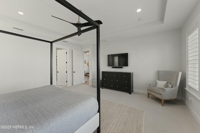 carpeted bedroom with a tray ceiling, recessed lighting, visible vents, and baseboards