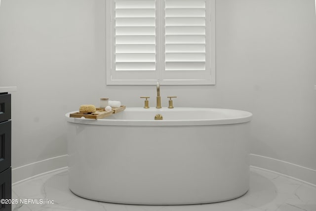 full bathroom with a soaking tub, marble finish floor, and baseboards