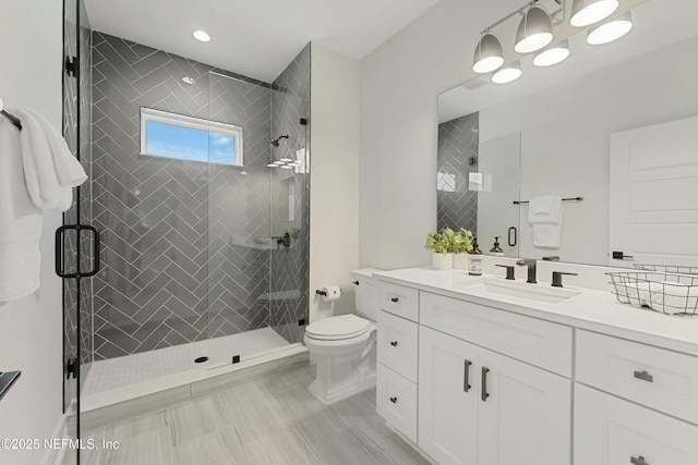 bathroom featuring a shower stall, toilet, and vanity