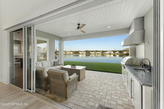 view of patio featuring area for grilling, a ceiling fan, a water view, and a sink