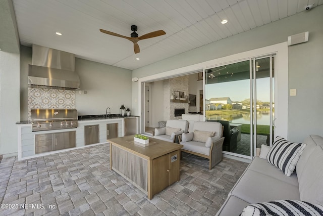 exterior space featuring recessed lighting, a large fireplace, a water view, and ceiling fan