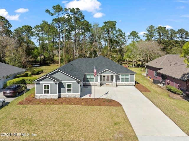 view of front of house featuring stone siding, a front yard, driveway, and a shingled roof