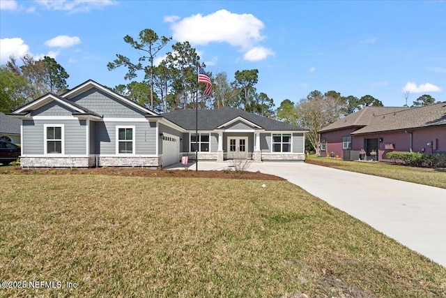 view of front of home featuring stone siding, an attached garage, concrete driveway, and a front lawn