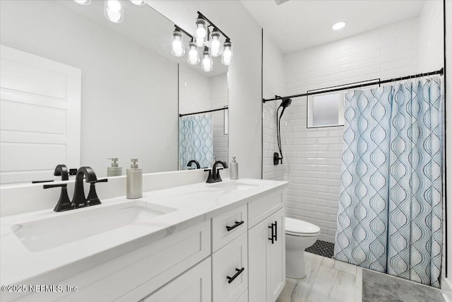 bathroom with a sink, tiled shower, toilet, and double vanity