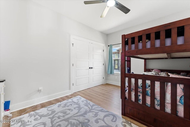 bedroom with a closet, ceiling fan, baseboards, and wood finished floors