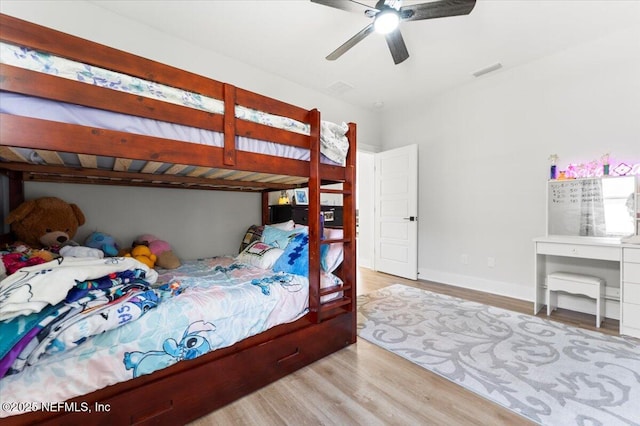 bedroom with a ceiling fan, wood finished floors, visible vents, and baseboards