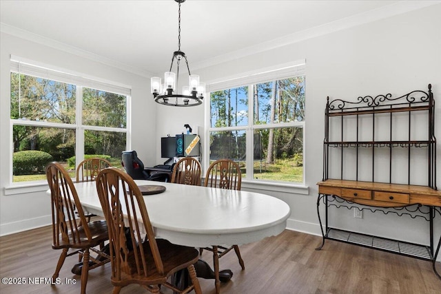 dining space with baseboards, an inviting chandelier, wood finished floors, and crown molding