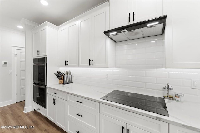 kitchen with under cabinet range hood, backsplash, white cabinets, and black appliances