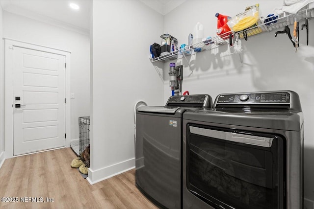 washroom with baseboards, light wood finished floors, washing machine and clothes dryer, laundry area, and crown molding