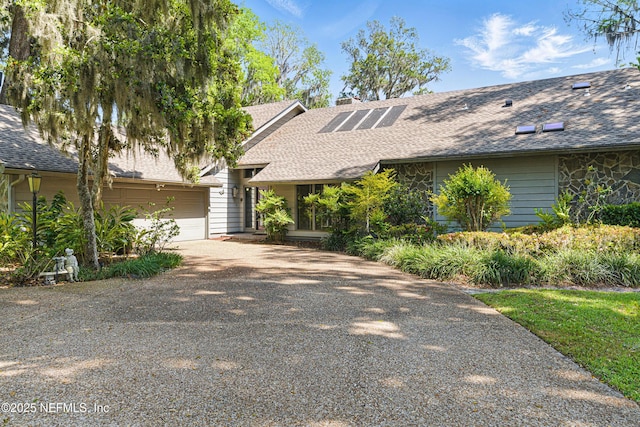 mid-century home featuring roof with shingles, a chimney, driveway, and a garage