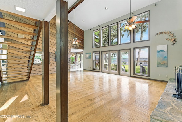 unfurnished living room featuring stairway, a ceiling fan, wood finished floors, and a towering ceiling