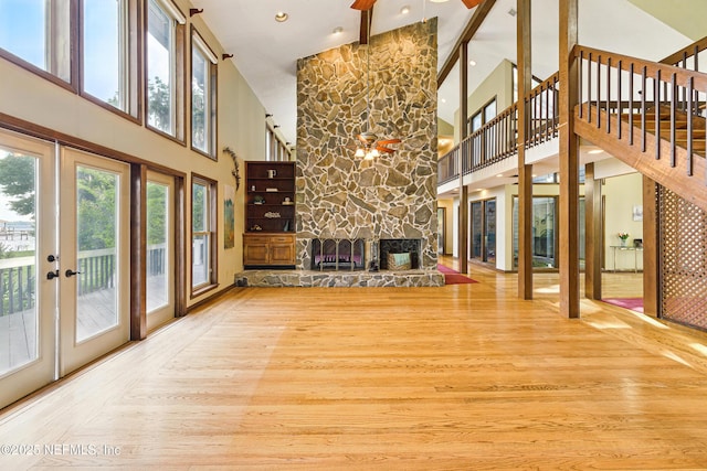 unfurnished living room featuring a ceiling fan, high vaulted ceiling, stairway, and a fireplace