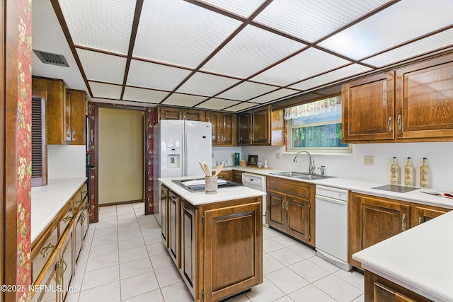kitchen featuring visible vents, a sink, light countertops, white appliances, and a kitchen island