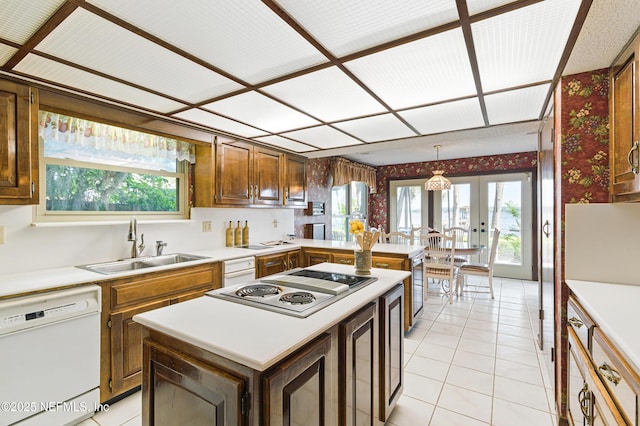 kitchen with light countertops, electric cooktop, dishwasher, and a sink