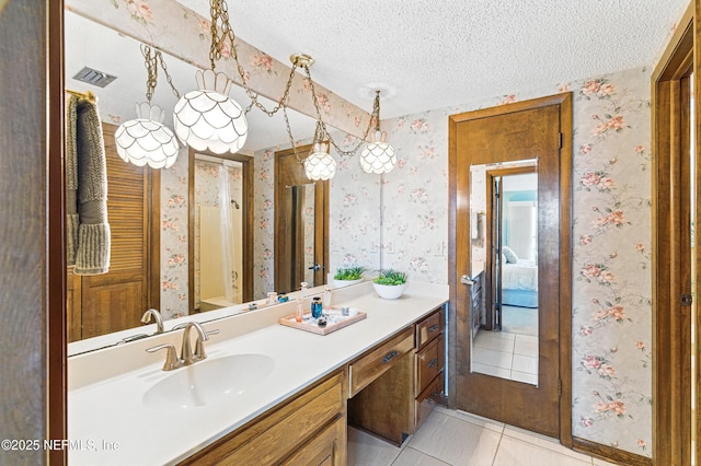 bathroom featuring a textured ceiling, wallpapered walls, visible vents, and tile patterned floors