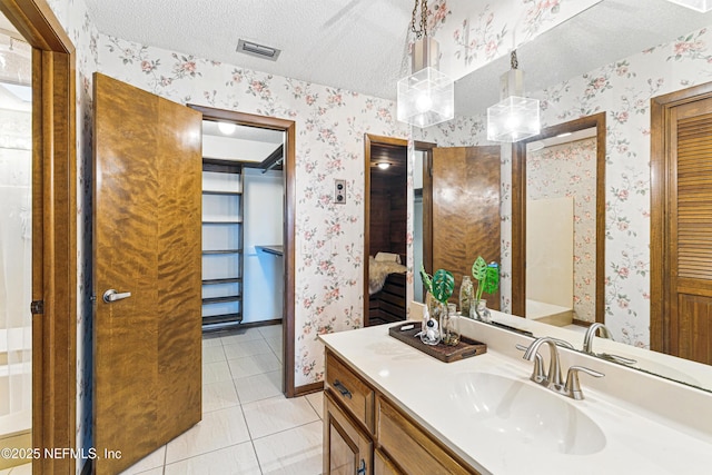 bathroom with vanity, a textured ceiling, tile patterned flooring, and wallpapered walls