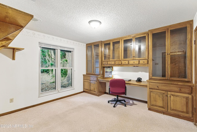 home office with light carpet, baseboards, built in desk, and a textured ceiling
