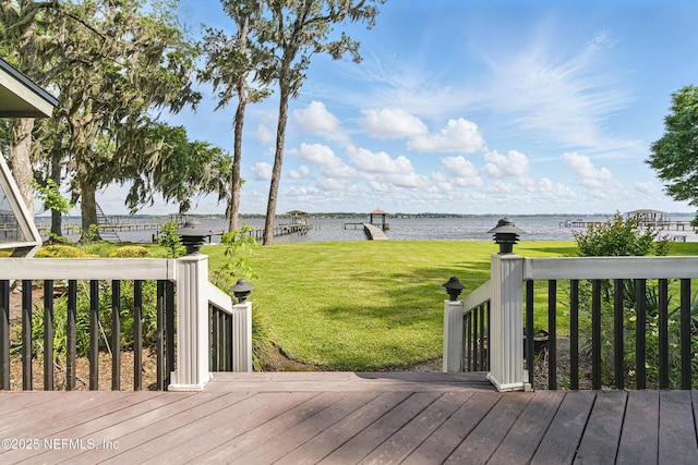 wooden terrace featuring a water view and a yard