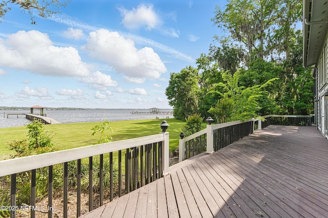 wooden terrace with a water view and a yard