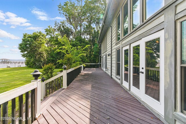 wooden deck featuring a water view, french doors, and a lawn