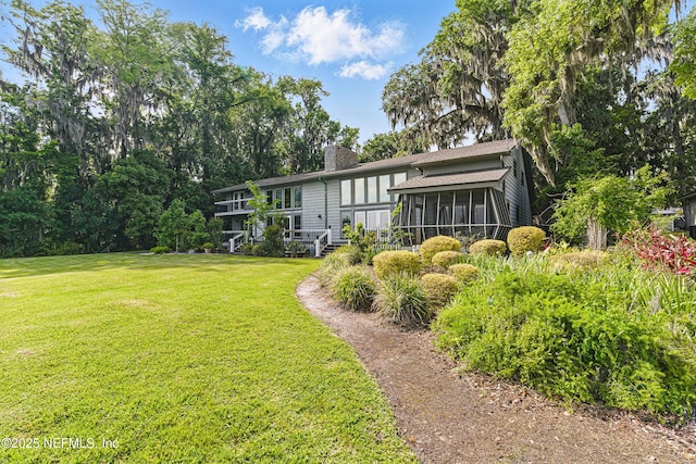 back of property featuring a yard, a sunroom, and a chimney