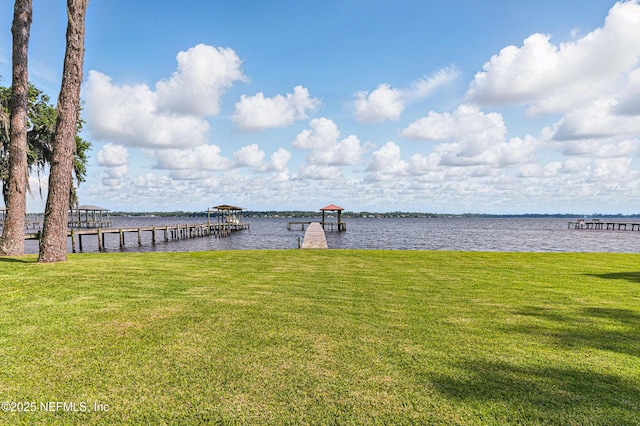 view of dock with a yard and a water view