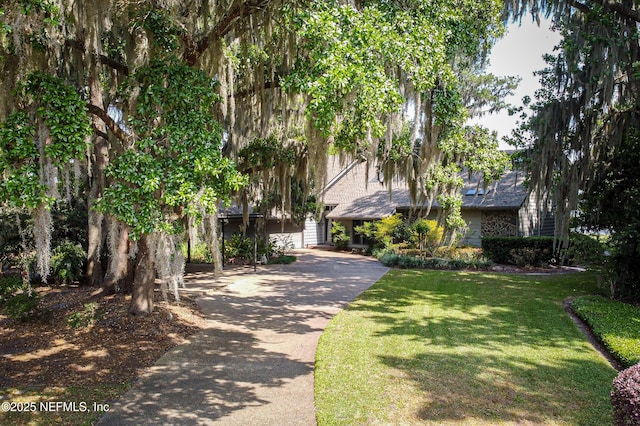 view of community with a yard, an attached garage, and concrete driveway