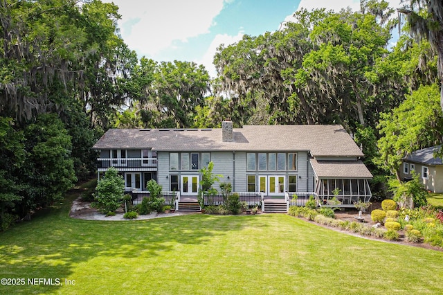 back of property featuring a sunroom, a lawn, a chimney, french doors, and a shingled roof