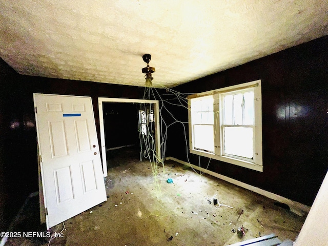 empty room featuring a textured ceiling and baseboards