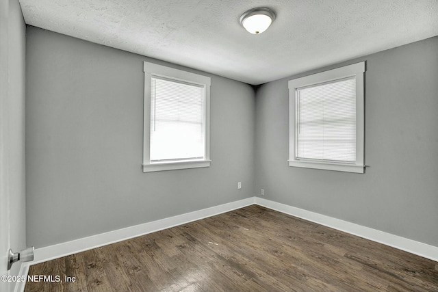 unfurnished room featuring baseboards, dark wood-type flooring, and a textured ceiling