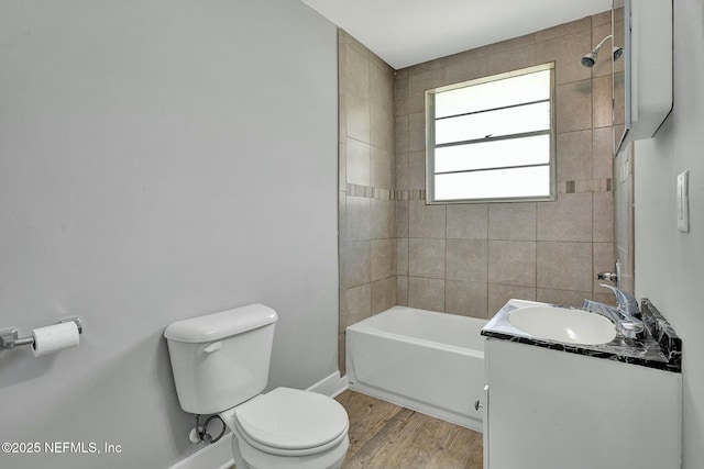 bathroom with toilet, wood finished floors, baseboards, bathing tub / shower combination, and vanity