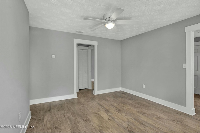 spare room featuring baseboards, wood finished floors, and a ceiling fan