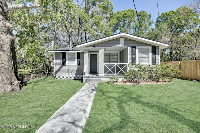 view of front facade featuring a porch, a front lawn, and fence