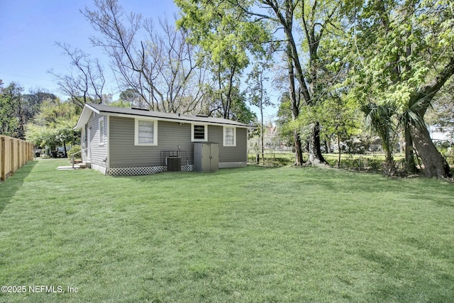 back of house featuring a yard, central AC unit, and fence