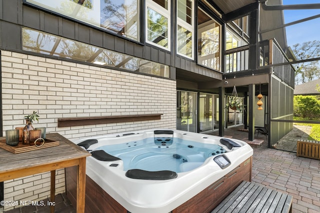 view of patio / terrace featuring glass enclosure and an outdoor hot tub