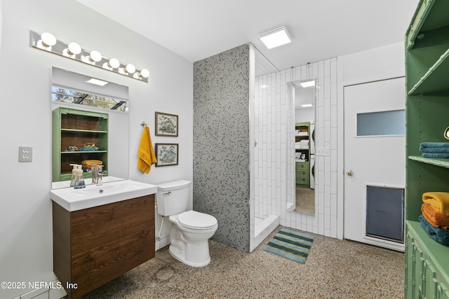 full bathroom with vanity, toilet, speckled floor, and tiled shower