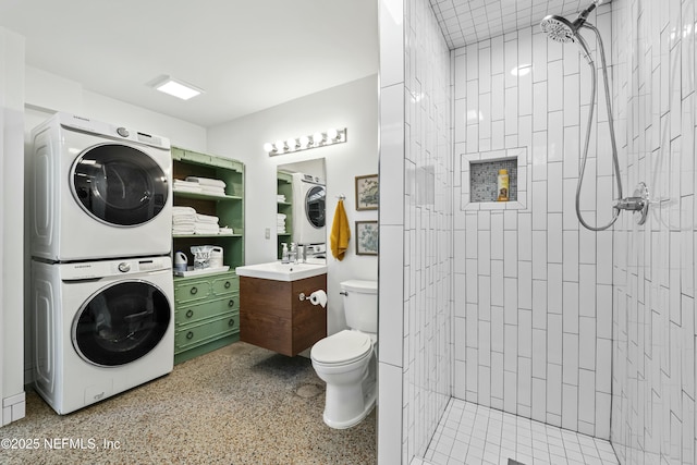 full bathroom with vanity, toilet, stacked washer / drying machine, and tiled shower