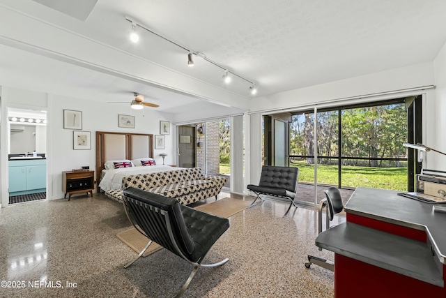 bedroom featuring speckled floor, a sink, access to exterior, rail lighting, and ensuite bathroom