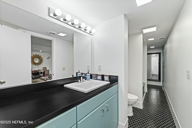 bathroom featuring visible vents, toilet, vanity, and baseboards