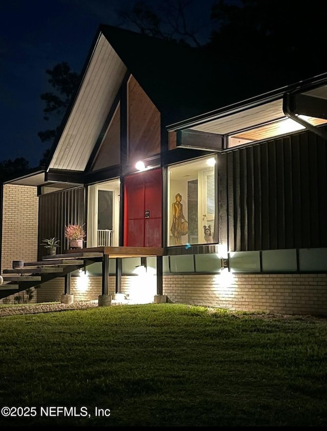 back of house at twilight featuring a yard and a sunroom